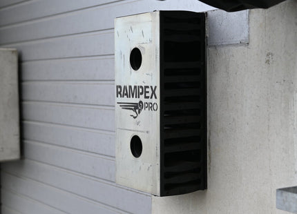 A metal dock buffer named RAMPEX-PRO mounted on a concrete ramp with a metal plate and branding visible.